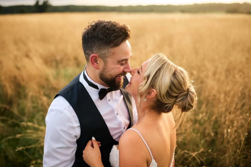 A newly married couple sharing a quiet moment in a golden field at Pentney Abbey
