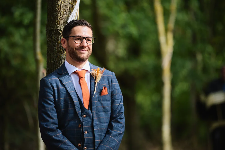 The groom waiting beneath the trees