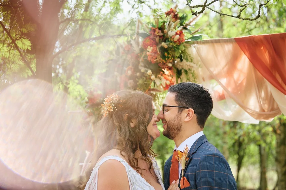 Maddi and Bobby kissing beneath the trees in warm woodland light